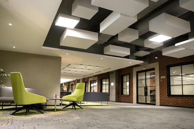 Contemporary office space featuring brick walls and unique ceiling design with bright lighting.